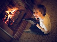 Boy with bellows sitting at fireplace — Stock Photo