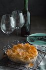 Traditional greek spinach pie spanakopita on baking rack and wine bottle — Stock Photo