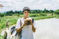 LA HABANA, CUBA - MAY 1, 2018: Serious young man with backpack drinking cocktail from coconut — Stock Photo