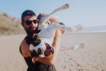 Man playing with dog on beach — Stock Photo