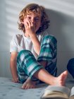 Laughing boy sitting on bed — Stock Photo