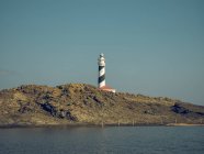 Lighthouse on hill and rippled sea water — Stock Photo