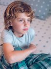 Thoughtful boy sitting on bed — Stock Photo