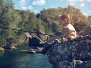 Garçon assis et pêche — Photo de stock
