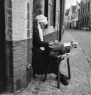 Colpo in bianco e nero di donna anziana seduta sulla strada del Belgio con artigianato nel tempo libero
. — Foto stock