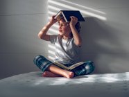 Menino com livros na cabeça e no colo — Fotografia de Stock