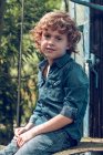 Мальчик, сидящий снаружи — стоковое фото