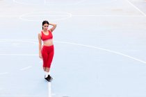 Jeune femme souriante debout sur un terrain de sport — Photo de stock