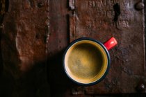 Tasse émail de café sur une surface en bois rustique — Photo de stock