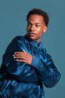 Portrait de jeune homme noir en tenue bleue avec les bras croisés regardant loin — Photo de stock
