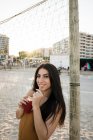 Молода доросла жінка з довгим волоссям насолоджується лимонадом на піщаному березі — стокове фото