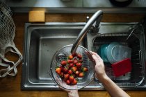 Human hands washing strawberries under sink tap — Stock Photo
