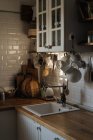 Интерьер кухни с белыми черепичными стенами и большим количеством посуды и приборов, составленных на полках и столешнице — стоковое фото
