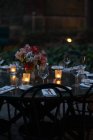 Mesa de ajuste decorada com velas e flores à noite no quintal — Fotografia de Stock