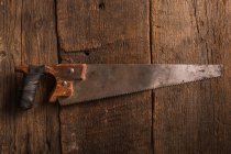 Carpenter rusty handsaw on wooden surface — Stock Photo
