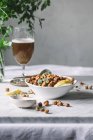 Composition du bol rempli de pois chiches épicés cuits au four sur la table avec boisson en verrerie vintage — Photo de stock