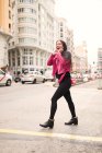 Mujer joven de moda en chaqueta rosa caminando por la calle y riendo - foto de stock