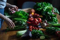 Вид на урожай женских рук, берущих горшки с элегантного стола со свежими здоровыми растительными и фруктовыми ингредиентами для приготовления пищи сверху — стоковое фото