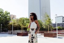 Елегантний афро-американських жінка говорити на смартфоні стоячи на місто вулиці на сонячний день — стокове фото