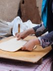 Женские руки катятся лист теста на деревянной доске — стоковое фото