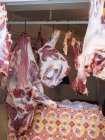 Part of huge raw beef hangs on hook in shadow of room — Stock Photo