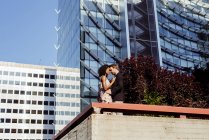 Sensual elegant couple embracing in front of modern buildings — Stock Photo