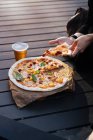 Primo piano di mani femminili che prendono il pezzo di pizza — Foto stock