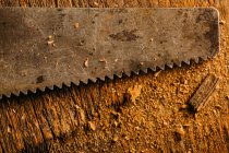Крупным планом ржавой ручной пилы на деревянной поверхности — стоковое фото