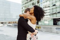 Happy multiracial couple embracing on city street together — Stock Photo