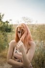 Jeune femme touchant les cheveux et posant au lac de campagne — Photo de stock