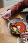 Man eating traditional Nordic red soup garnished with herbs — Stock Photo