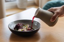 Pessoa que prepara sopa de beterraba nórdica em tigela cinza na mesa de madeira — Fotografia de Stock