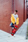 Подросток со скейтбордом на углу — стоковое фото