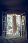 Wedding dress hanging on window curtain — Stock Photo