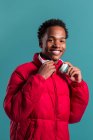 Trendy man in red puffy jacket and headphones on blue background — Stock Photo