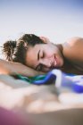 Nahaufnahme einer lächelnden jungen Frau, die am Strand liegt — Stockfoto