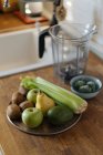 Свіжі зелені овочі та фрукти на тарілці на дерев'яній стійці на кухні — стокове фото