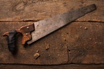 Carpinteiro serra de mão enferrujada na superfície de madeira — Fotografia de Stock