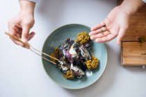 Mãos humanas enfeite prato de frutos do mar nórdicos com mexilhões e molho de creme no prato — Fotografia de Stock