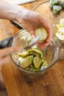 Mani umane peeling kiwi metà con cucchiaio e miscelazione con frutti in ciotola frullatore per frullato verde — Foto stock