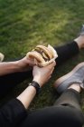 Woman holding burger while sitting on grass — Stock Photo