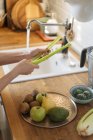 Mains féminines laver les légumes verts dans l'évier sous le jet d'eau dans la cuisine — Photo de stock