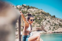 Giovane ragazza in abiti estivi appoggiata su corrimano in legno sulla spiaggia — Foto stock