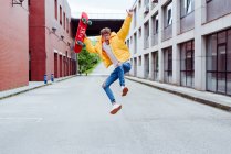 Feliz y emocionado adolescente saltando con monopatín - foto de stock