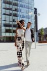 Elegant multiracial couple holding hands while walking in modern city — Stock Photo