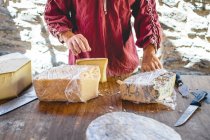 Couper la main du vendeur en donnant au client un morceau de fromage sur le couteau pour la dégustation — Photo de stock