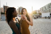 Young women enjoying drinks in soft light at city coastline — Stock Photo