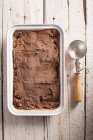 Gelato al cioccolato fatto in casa in scatola con misurino su superficie di legno — Foto stock