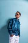 Smiling black man in blue bomber jacket standing on blue background — Stock Photo
