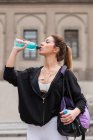 Mulher esportiva bebendo água de garrafa na rua — Fotografia de Stock